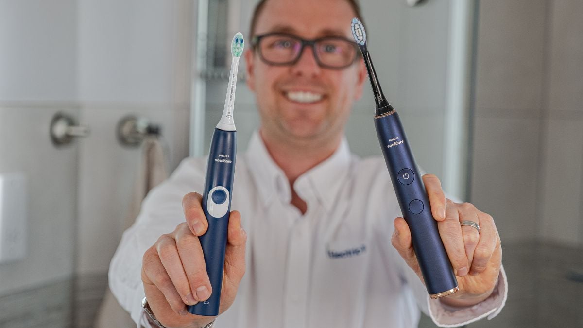 2 Sonicare electric toothbrushes being held up, 1 in each hand.