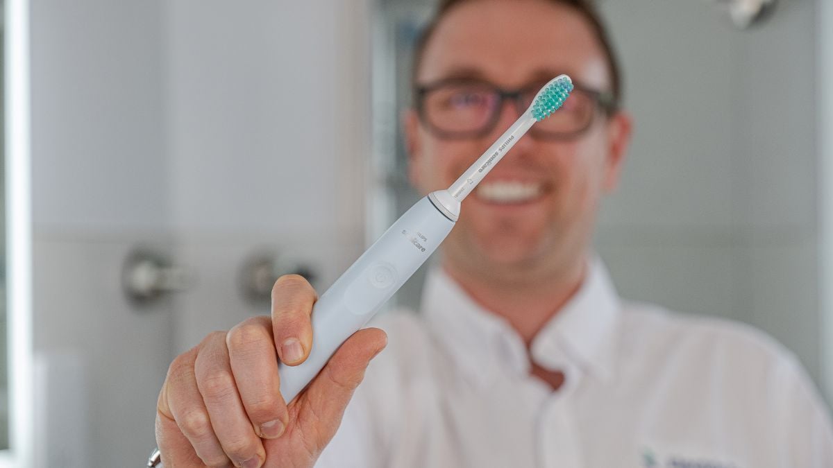 A Sonicare 2100 Series toothbrush being held up in hand